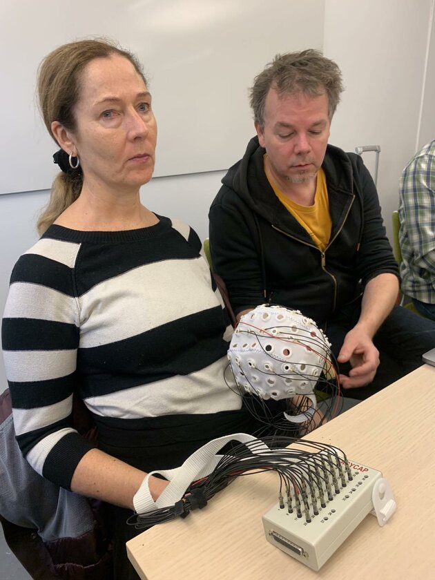 Pia-Lena (SRF) håller i en EEG-cap och Per (syntolk) beskriver hur utrustningen ser ut.